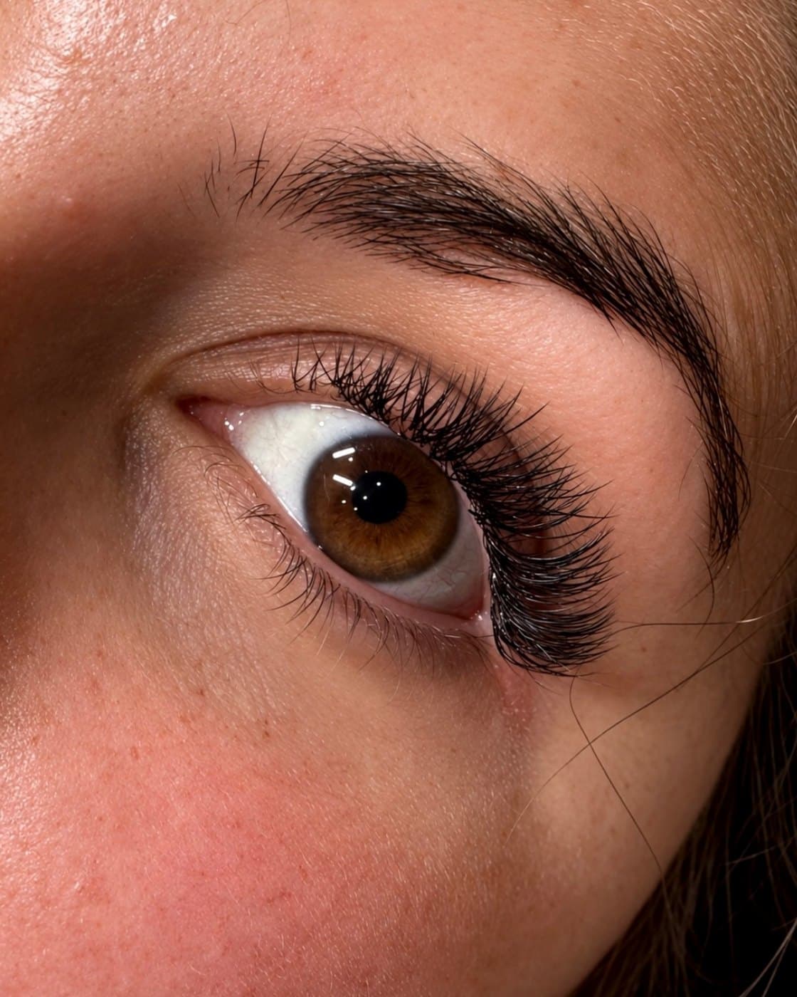 Gros plan d'un œil marron après une pose d'extensions de cils effet naturel